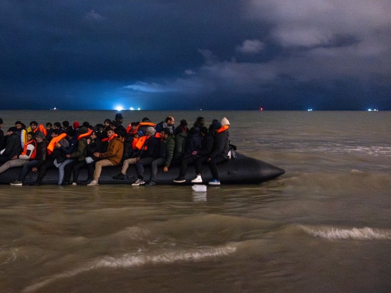 TOPSHOT - Migrants board a smuggler's inflatable dinghy in an attempt to cross the English Channel, on Bleriot beach in Sangatte, near Calais, northern France on October 30, 2024. (Photo by Sameer Al-DOUMY / AFP)